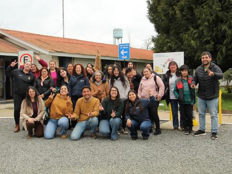 Un grupo de personas sonrientes se reúne frente a un edificio en un día nublado.