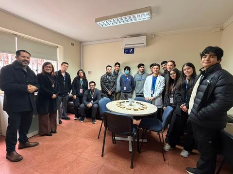 Un grupo de jóvenes y adultos sonrientes posan en una sala después de una actividad en común.