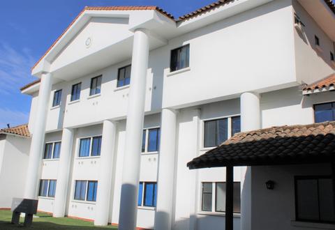 Edificio moderno de fachada blanca con columnas y ventanas azules.