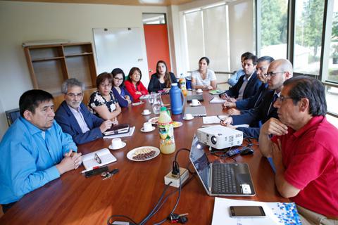 Reunión de trabajo en una sala con varias personas sentadas alrededor de una mesa.