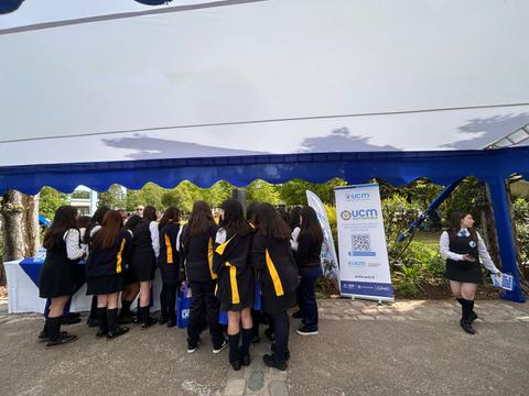Grupo de estudiantes en un evento al aire libre bajo una carpa.