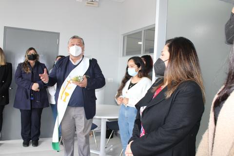 Una reunión donde un hombre con una banda se dirige a un grupo de personas que lo observan atentamente.