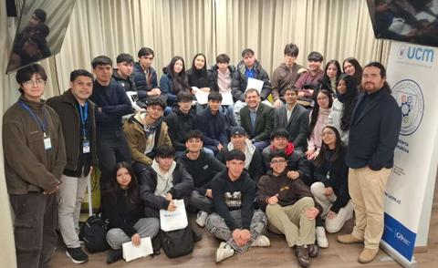 Un grupo de estudiantes posando en una sala con un banner de la UCM.