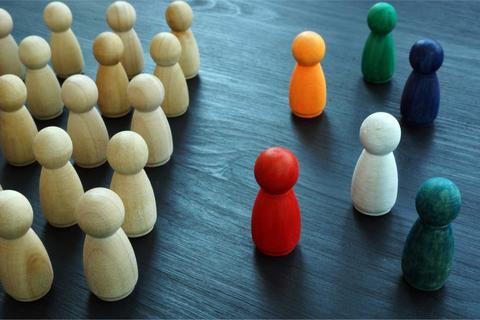 Una colección de figuras de madera de diferentes colores organizadas en grupos sobre una mesa oscura.