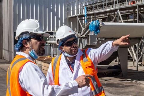Dos trabajadores conversando y señalando en un ambiente industrial.