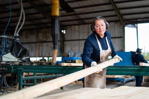 Una mujer trabaja con madera en un taller de carpintería.