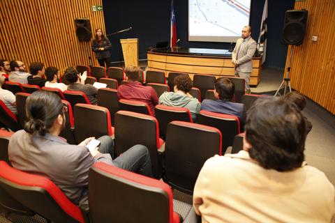 Una presentación en un auditorio con varias personas sentadas frente a un expositor.