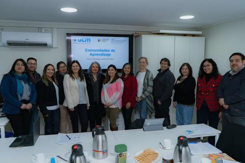 Grupo de personas reunidas en una sala, presentando un tema sobre comunidades de aprendizaje.