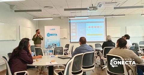 Un presentador expone en un aula frente a un grupo de asistentes.