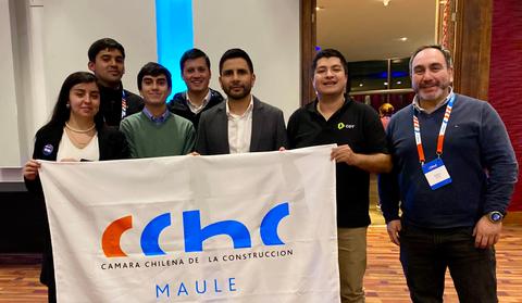 Un grupo de jóvenes sosteniendo una bandera de la Cámara Chilena de la Construcción en un evento.