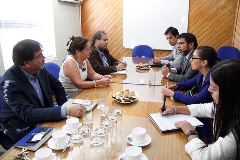 Una reunión de trabajo en una sala con varias personas sentadas alrededor de una mesa.