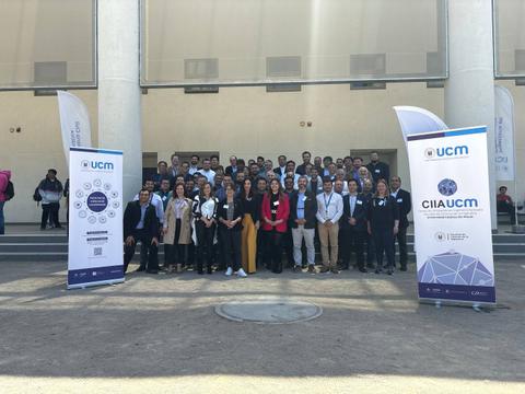 Grupo de personas posando en un evento al aire libre con pancartas de UCM y CIIA UCM.