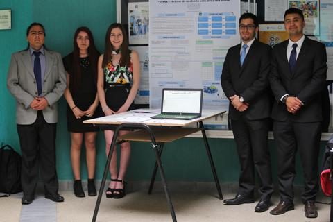 Grupo de estudiantes posando frente a un póster en un evento académico.