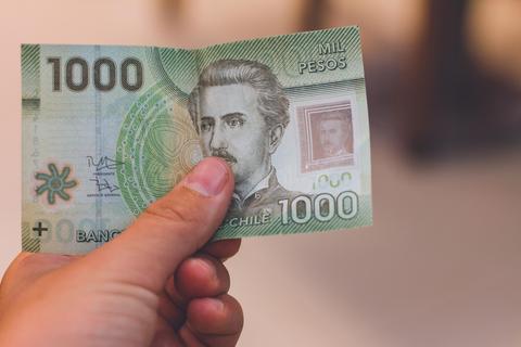 Un billete de mil pesos chilenos sostenido con una mano.