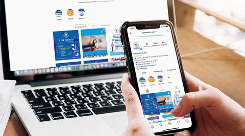Una persona usando un teléfono móvil mientras navega por una página de Instagram en una computadora portátil.