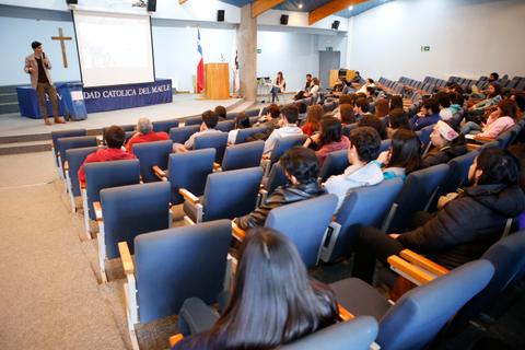 Una conferencia se lleva a cabo en un auditorio con un gran número de asistentes mirando hacia el ponente.