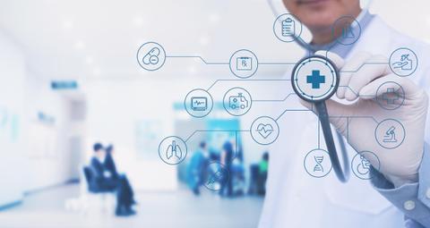 Un profesional de la salud sostiene un estetoscopio mientras muestra iconos relacionados con la medicina en un entorno hospitalario.