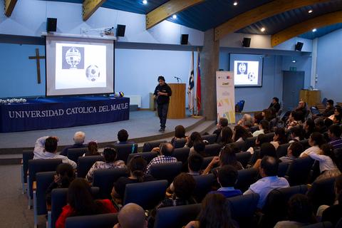Un ponente está hablando frente a un público en una conferencia en la Universidad Católica del Maule.