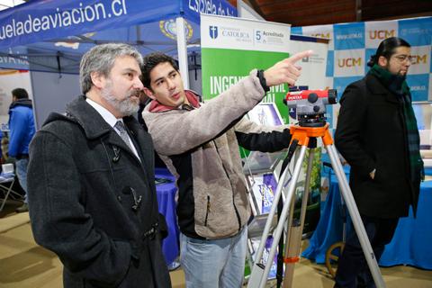 Dos hombres conversan sobre un instrumento de medición en un evento académico.