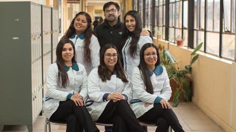 Un grupo de seis personas posando en un pasillo de una institución educativa.