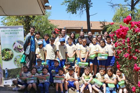 Un grupo de niños y adultos posan sonrientes frente a un cartel que promueve la conservación del bosque.