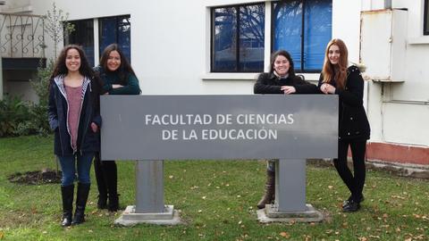 Cuatro estudiantes posan frente a un cartel de la Facultad de Ciencias de la Educación.