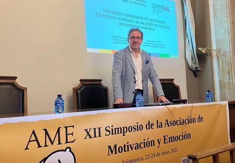 Un ponente se presenta en un simposio sobre motivación y emoción en un ambiente académico.