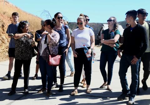Un grupo de personas conversando y caminando al aire libre en un día soleado.