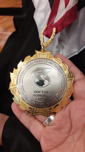 Una medalla dorada que representa un título honorífico de Doctor Honoris Causa.