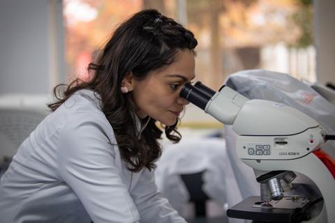 Una mujer observa a través de un microscopio en un laboratorio.