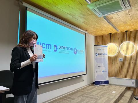 Una persona presenta un documento frente a una pantalla en un evento.