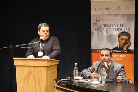 Dos personas discutiendo en un evento sobre ciencia y fe en una universidad.