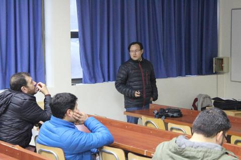 Un hombre presenta frente a un grupo de personas en un aula.
