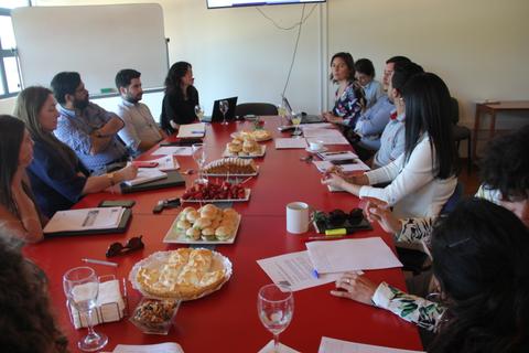Reunión de trabajo con un grupo de personas conversando en una mesa llena de alimentos.