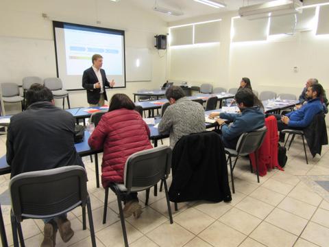 Un grupo de personas asiste a una presentación en un salón de clases.