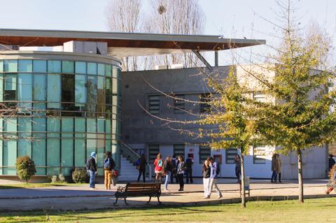 Un grupo de personas camina frente a un edificio moderno con grandes ventanales y áreas verdes alrededor.