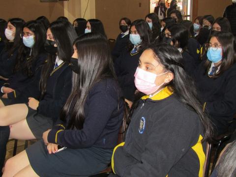 Un grupo de estudiantes sentados en un aula, usando mascarillas de diferentes colores.