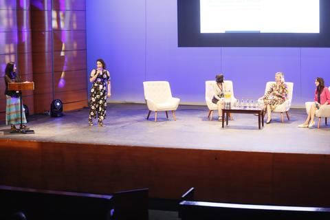 Una conferencia con varias ponentes en un escenario iluminado.