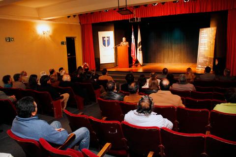 Un orador se presenta en un escenario frente a una audiencia en un teatro.