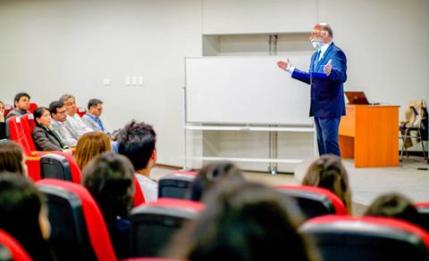 Un ponente da una charla frente a una audiencia en un salón de clases.