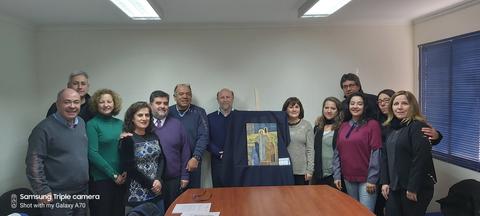 Un grupo de personas posando en una sala de reunión con una obra enmarcada en el centro.