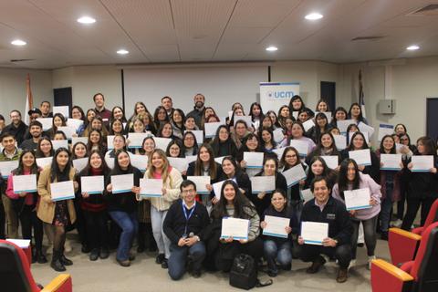 Un grupo grande de personas posando con certificados en un evento de la UCM.