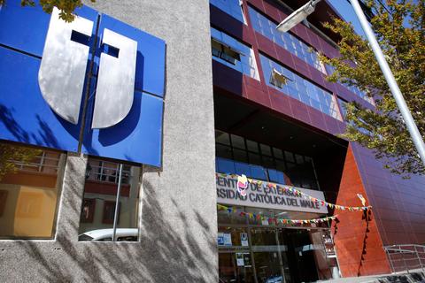 La imagen muestra la fachada de un edificio con un logo y un letrero de una universidad.