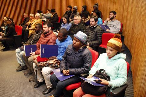 Un grupo de personas sentadas en un auditorio, esperando un evento.