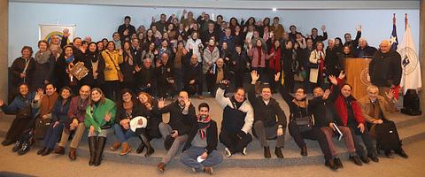 Una gran reunión con un grupo diverso de personas sonriendo y levantando las manos en señal de alegría.