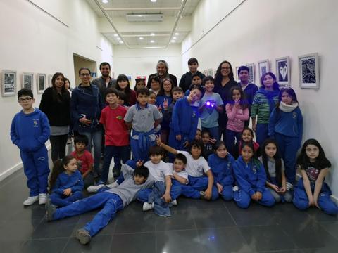 Un grupo de niños y adultos posan juntos en una galería de arte.