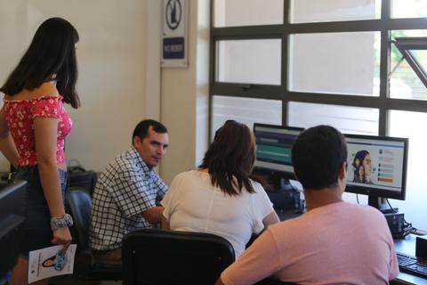 Un grupo de personas se encuentra en una habitación utilizando computadoras y conversando entre sí.