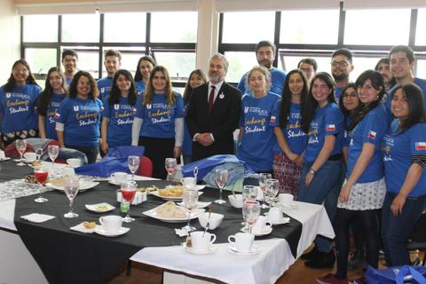 Un grupo de estudiantes en una reunión celebrando con camisetas azules y un ambiente festivo.