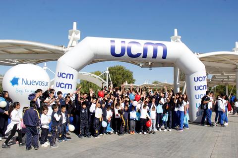 Un grupo de estudiantes celebra un evento bajo un arco inflable con las letras UCM.