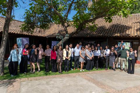 Un grupo de personas posando en un evento al aire libre frente a un edificio chileno.